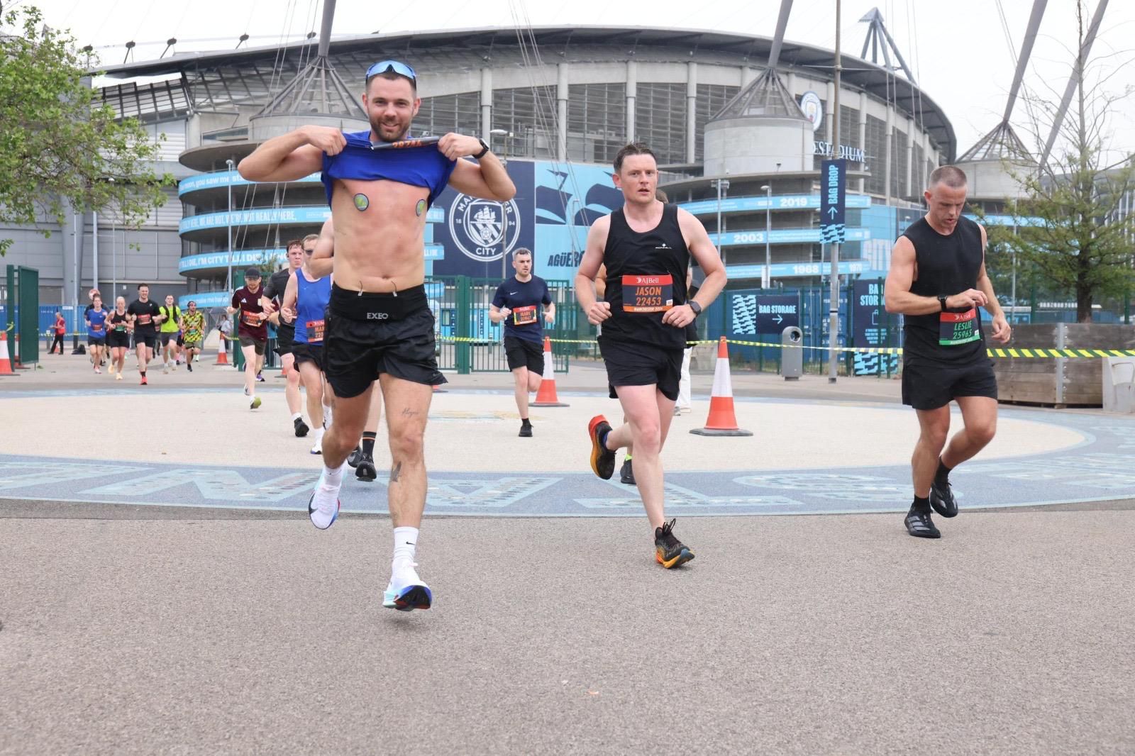 Runner lifting his vest mid-race to show No Rub Club tape
